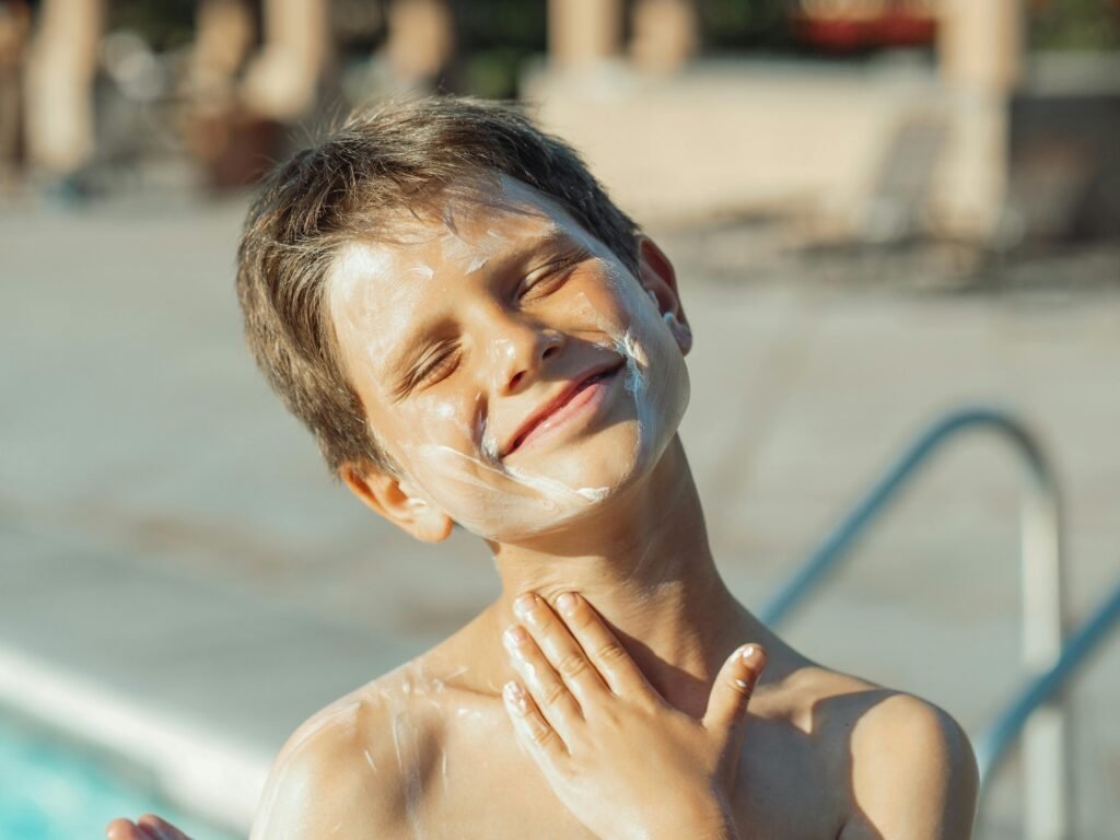 A boy rubbing sunscreen on himself