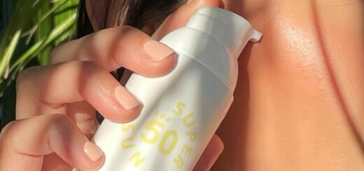 A woman putting a sunscreen bottle close to her face