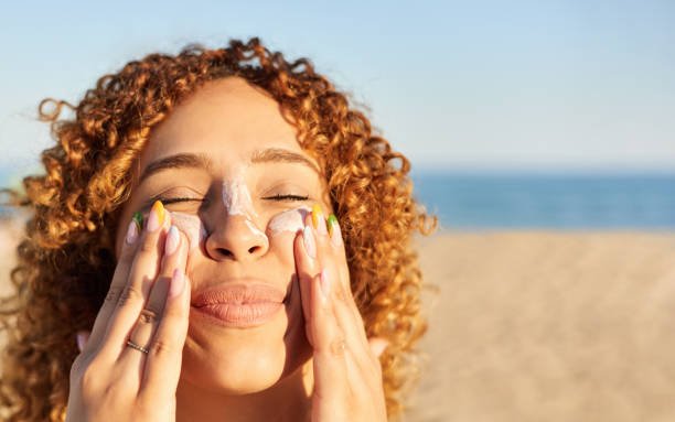 A woman applying face sunscreen