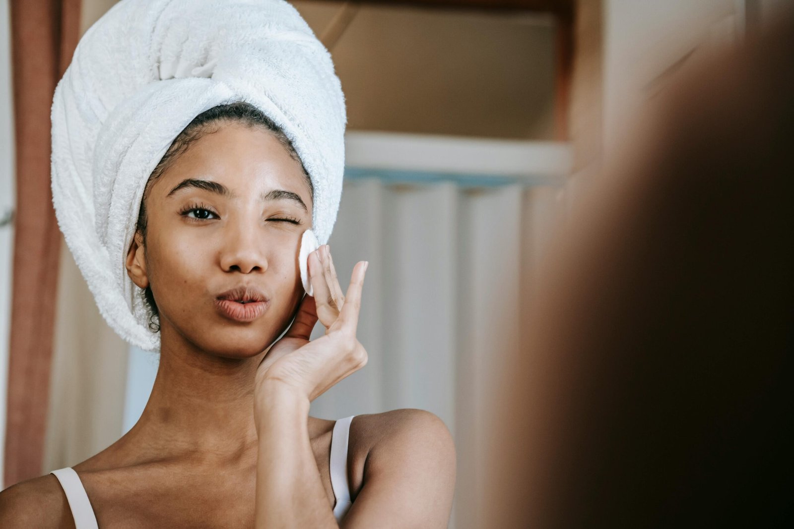 A woman using a cotton pad and comparing toner vs. astringent