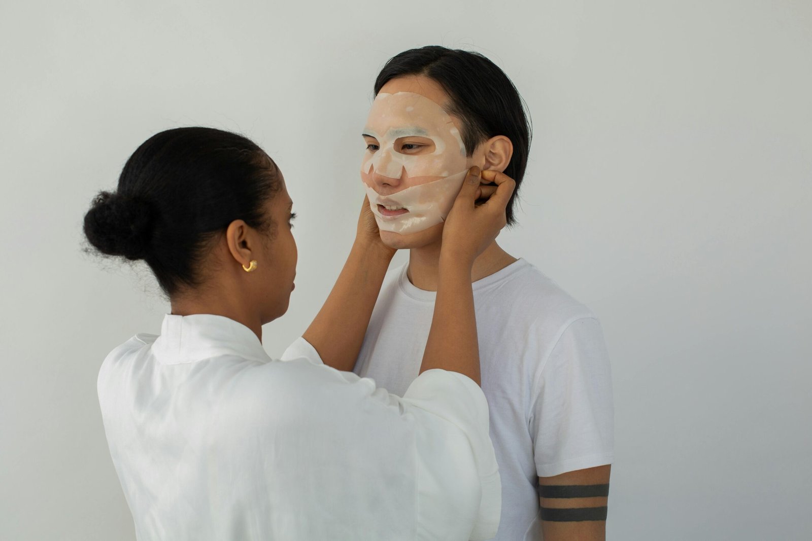 A woman putting a face mask on a man's face