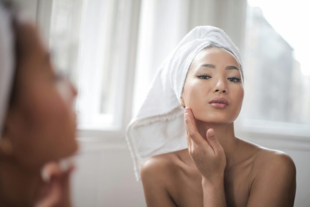 A woman looking in the mirror and checking for results from using hyaluronic acid